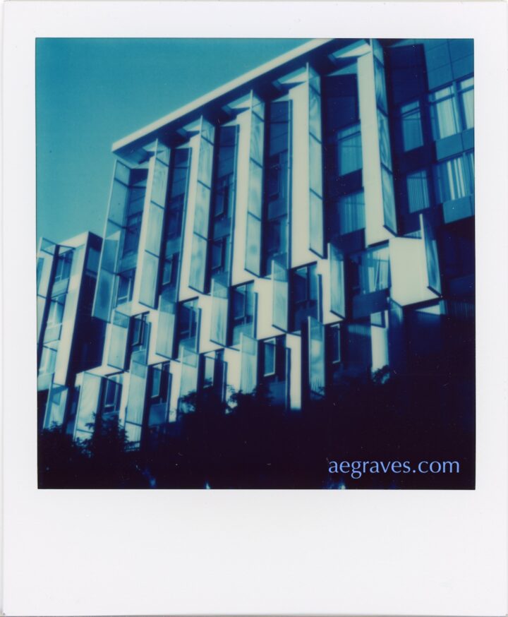 Blue, black and white image of a tall building with large louvers