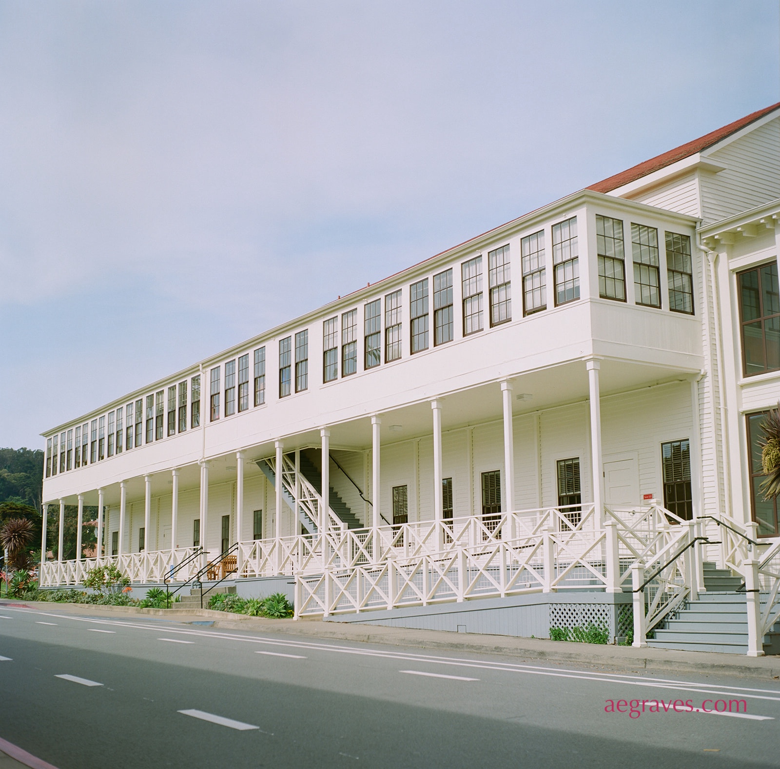 Long Rear Porch: a white building with an enclosed upper porch and exposed downstairs one shows perspective as the distant end of the building looks smaller
