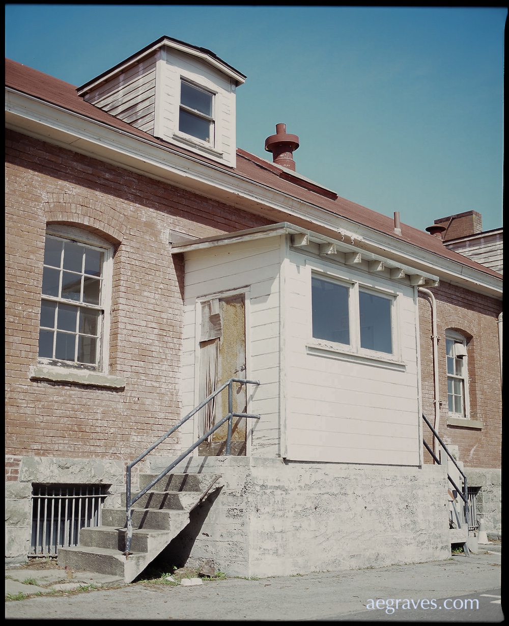 Historic red brick building with concrete steps leading to enclosed rear porch