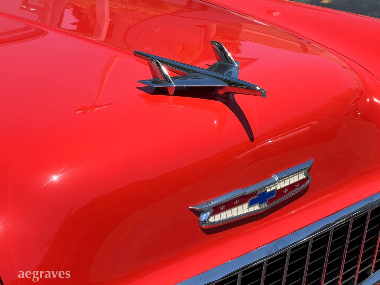 Chrome jet hood ornament on a classic, primary red Chevy