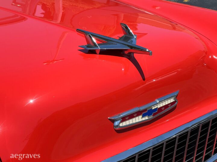 Chrome jet hood ornament on a classic, primary red Chevy