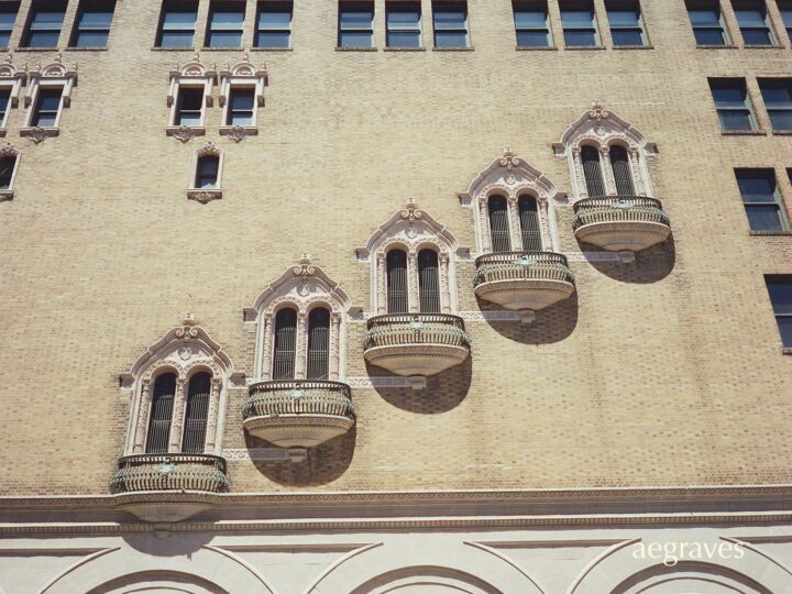 Five ornate balconie on the gold-yellow brick exterior of the Golden Gate Theater