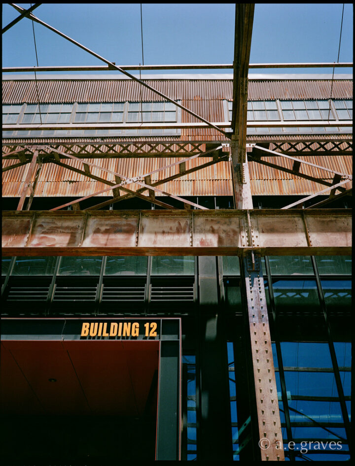 Heavily textured metal walls, beams, and posts, with Building 12 written in bright orange 3D letters