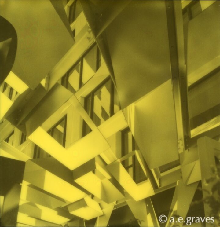 Monochrome black and yellow Polaroid image of a highly geometric but irregular metal patio roof