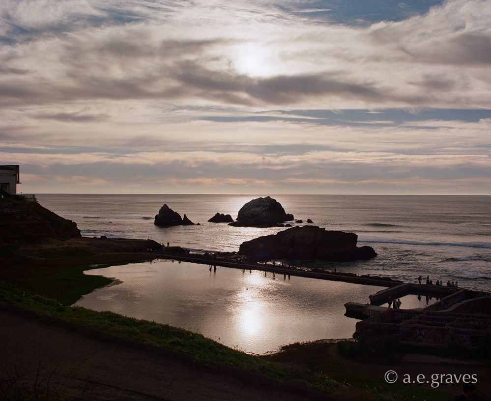 Sutro Baths are nearly in silhouette as the sun reflects on the flooded largest pool