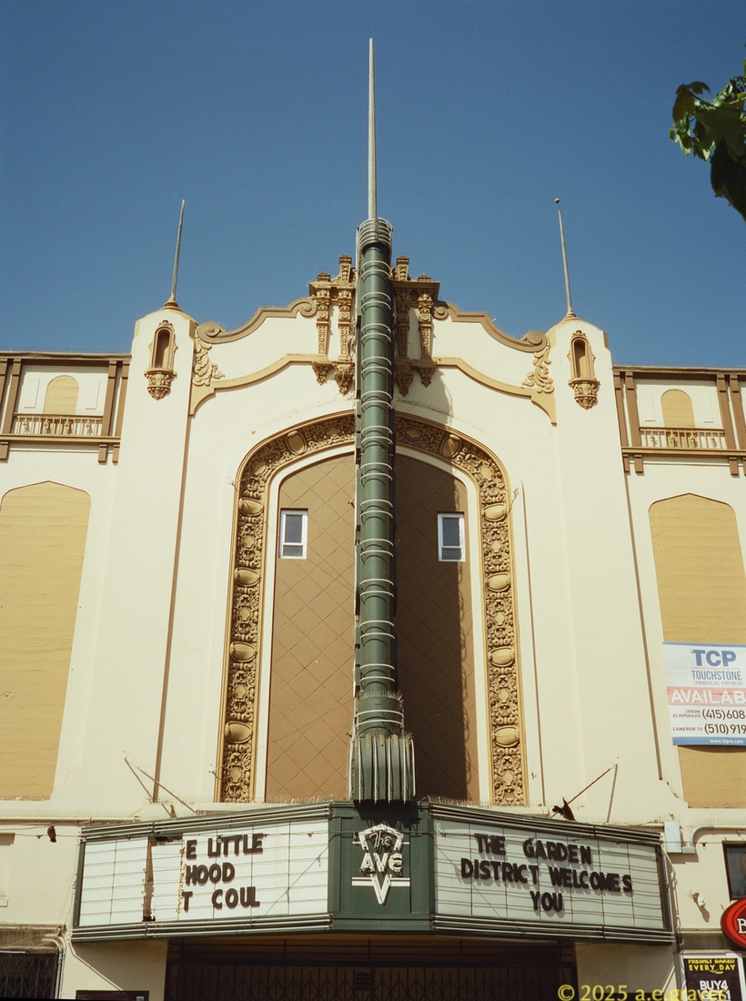 The movie theater as seen from directly across the street, so the marquee is just a green post; the symmetry of the building's decorations is more apparent