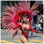 A dancer in an elaborate red, feathered costume with a complex headdress and sparkly bodysuit