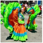 Dancers flaring their orange, lime green, and teal sequined skirts