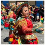 Detail of a woman performing in Carnaval primarily in teal, yellow, and primary red