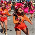 Dancers rocking out in orange costumes with multi-color flower headgear