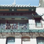 Ornate facade with a multicolored red and green metalwork balcony