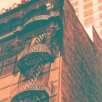 Orange and green image of an elaborate fire escape and rough brick wall