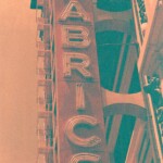 Orange and green image of a vertical neon sign reading FABRIC