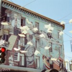 A mural on a pale green background with flying books (art installation) in the foreground