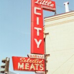 A tall, red marquee with neon letters for Little City Meats