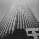 Monochrome image looking upward at a faceted cylindrical building