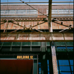 Heavily textured metal walls, beams, and posts, with Building 12 written in bright orange 3D letters