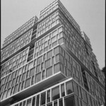 Monochrome image of a building of stacked box forms with an irregularly gridded curtain wall