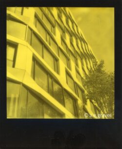 Monochrome black and yellow Polaroid image of a complex geometric facade with about nine stories visible